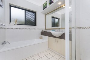 A modern bathroom with a bathtub, a sink, and a large mirror. - Oceania Beach Paradise (Yamba)