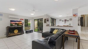 A modern living room with a black leather sofa, a wooden coffee table, and a large painting on the wall. - Oceania Beach Paradise (Yamba)