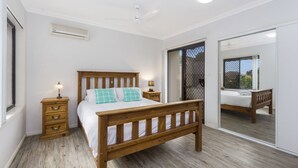 A bedroom with a wooden bed, a nightstand, a dresser, and a large mirror. - Oceania Beach Paradise (Yamba)