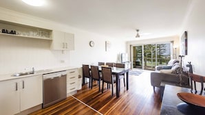 Uma cozinha moderna com armários brancos, lava-louças e uma área de jantar com mesa e cadeiras.