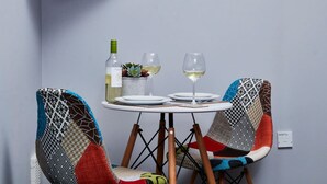 A dining table with two chairs, a bottle of white wine, and two glasses on it. - Stylish Apt Near EMA; Gym & Pool Access, Fast WiFi (Castle Donington)