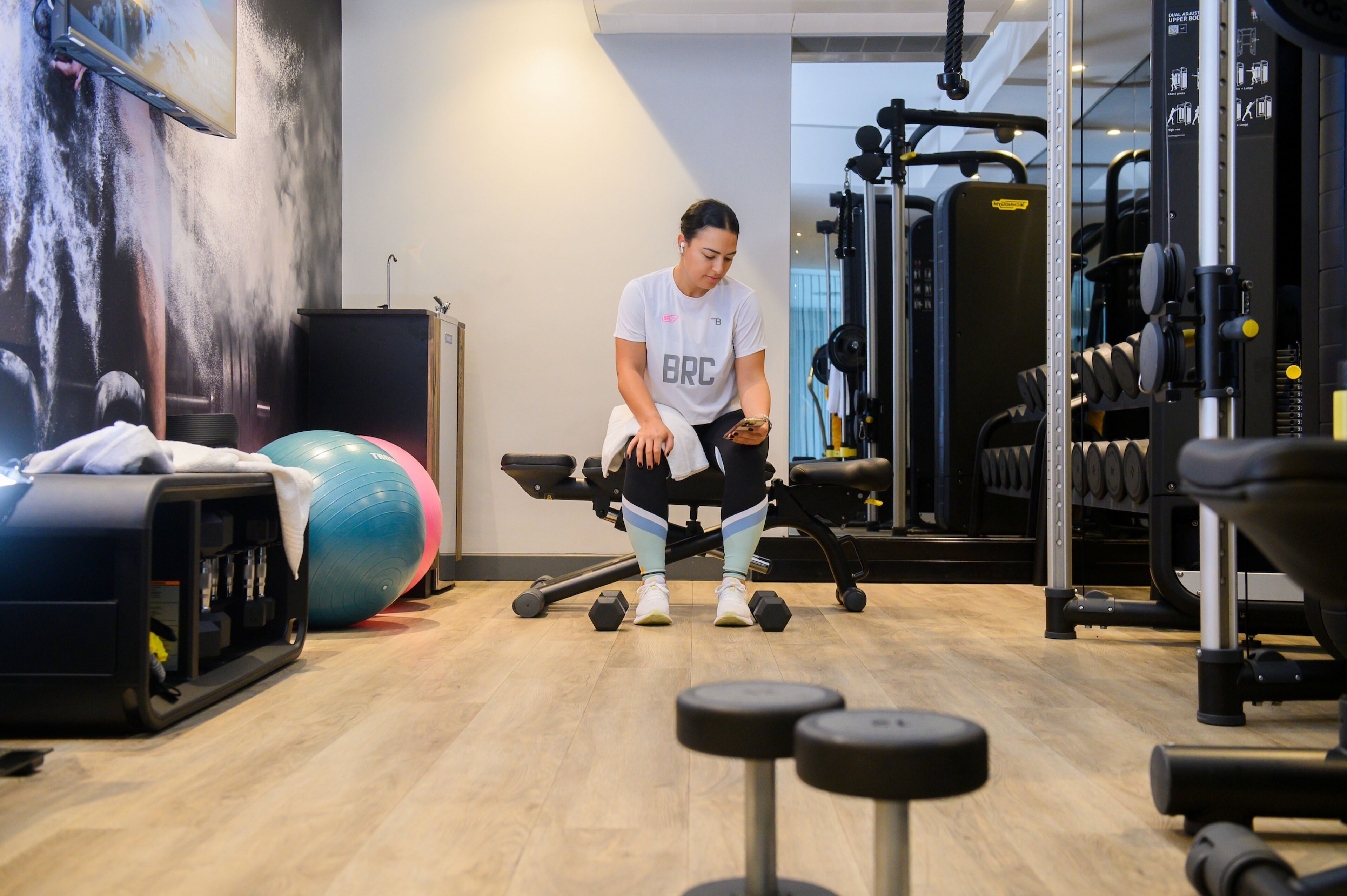 Et fitnessrum med træningsudstyr, en stor træningsbold og et tv på væggen.