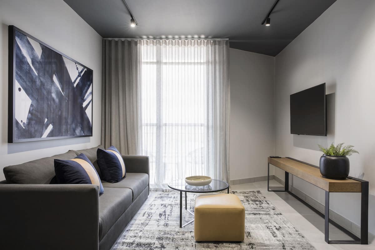 A modern living room with a sofa, a coffee table, a bench, and a large abstract painting on the wall.