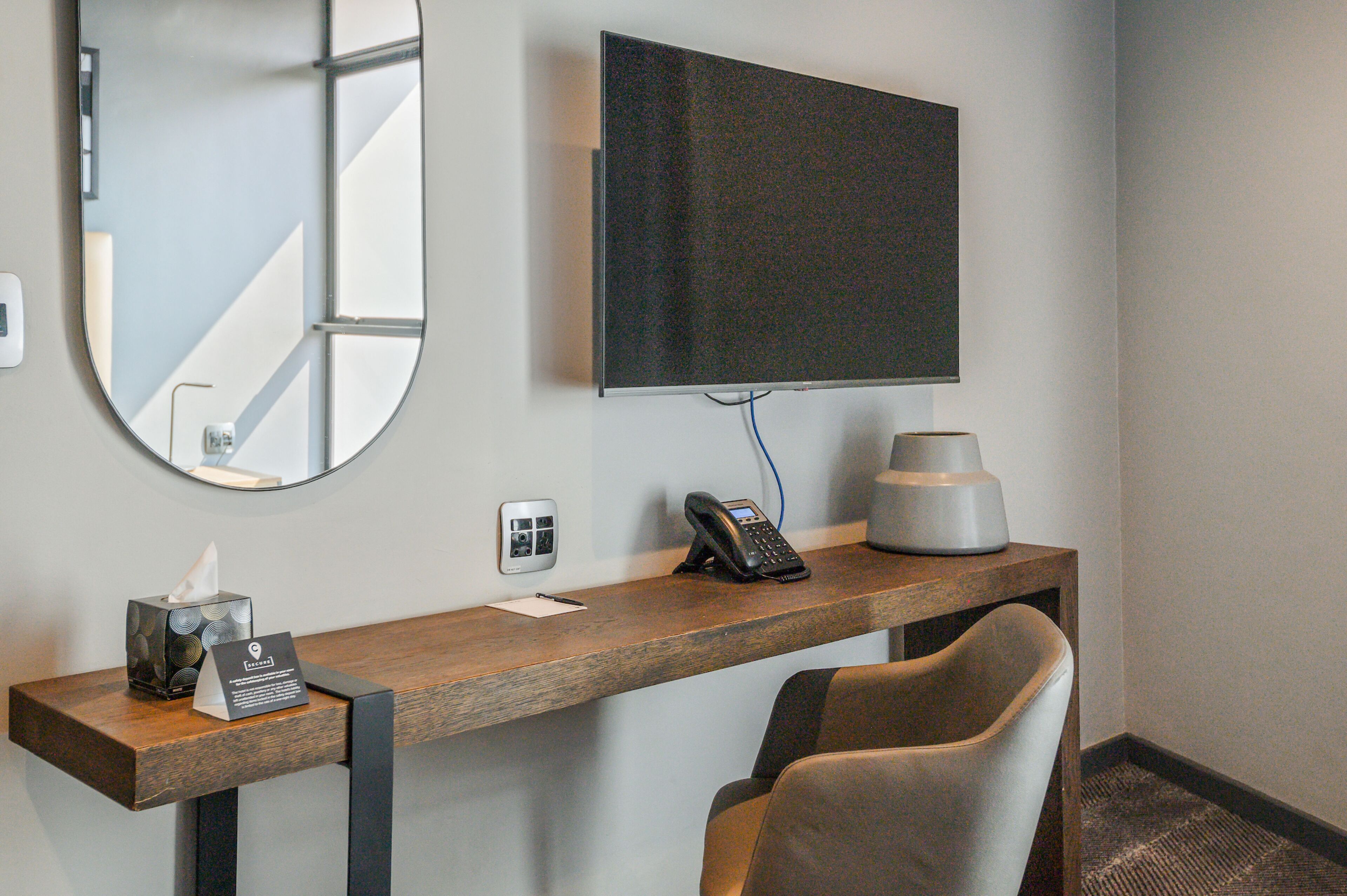A hotel reception desk with a flat-screen TV, a telephone, a tissue box, and a small sign.