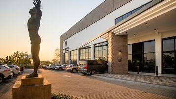 Un bâtiment moderne doté d’un parking, d’une sculpture et d’une enseigne indiquant « The Capital Hotel ».