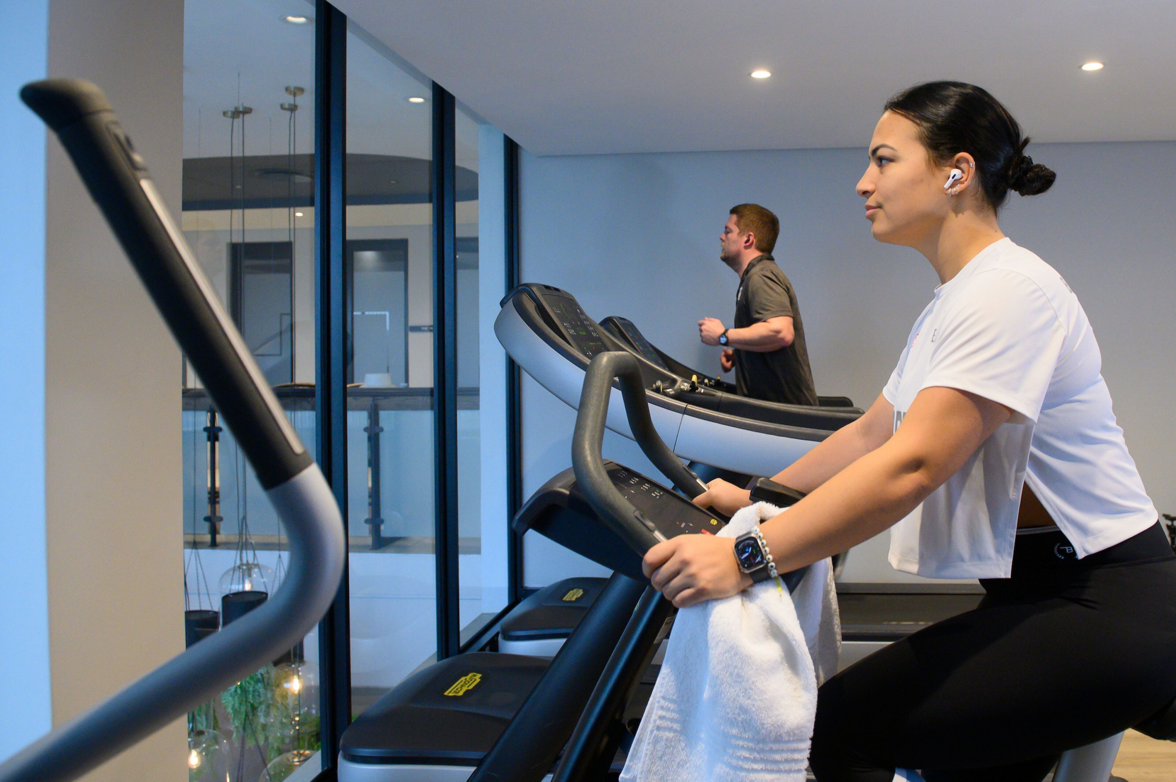 A gym with treadmills and a glass wall.