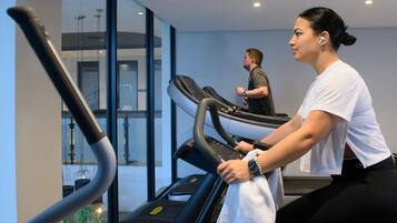 A gym with treadmills and a glass wall.