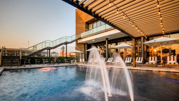 A pool area with a water fountain, lounge chairs, and a staircase leading to an upper level. - The Capital Mbombela (Mbombela)