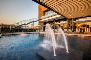 A pool area with a water fountain, lounge chairs, and a staircase leading to an upper level. - The Capital Mbombela (Mbombela)