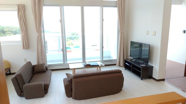 Ein Wohnzimmer mit zwei Sofas, einem Couchtisch und einem Fernseher auf einem Schrank.