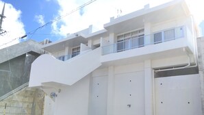 Ein modernes, zweistöckiges Gebäude mit Flachdach, großen Garagentoren und einem Balkon im oberen Geschoss.