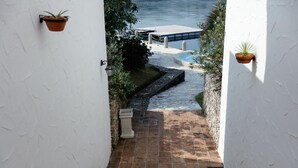 A narrow pathway leading to a dock over water, flanked by white walls and potted plants. - Miyako Resort Shima Bayside Terrace (Shima)