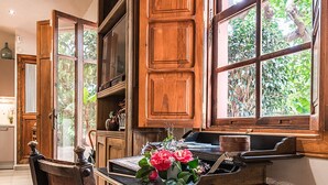 Une table à manger en bois avec une chaise, une fenêtre donnant sur un paysage verdoyant et des armoires en bois.