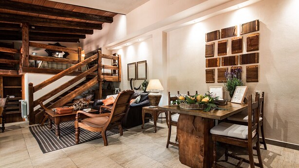 Un salon chaleureux avec un escalier en bois, une table à manger avec des chaises et un mur recouvert de lambris en bois.