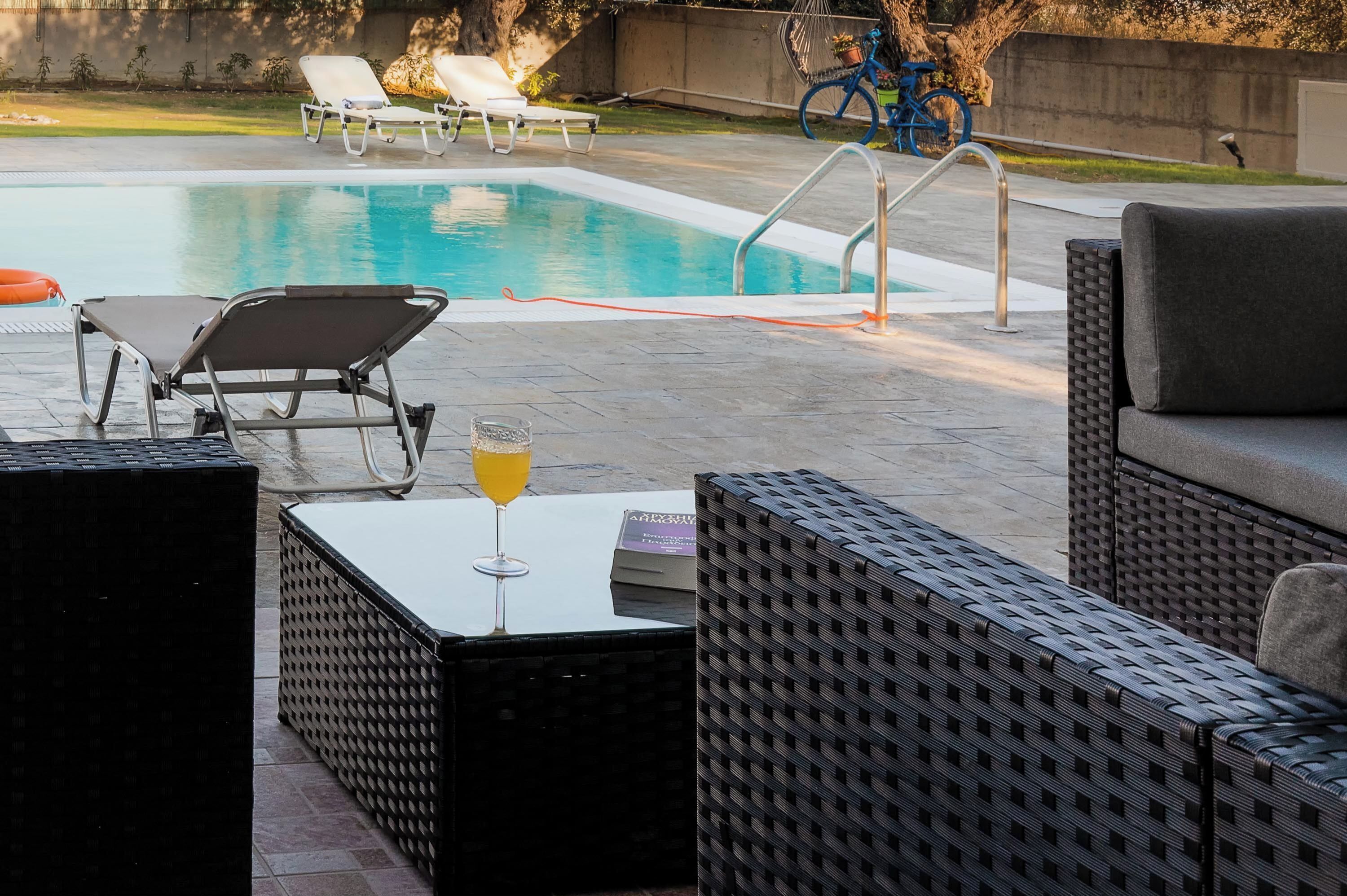 Una piscina con lettini, un tavolo con un drink e una bicicletta sullo sfondo.
