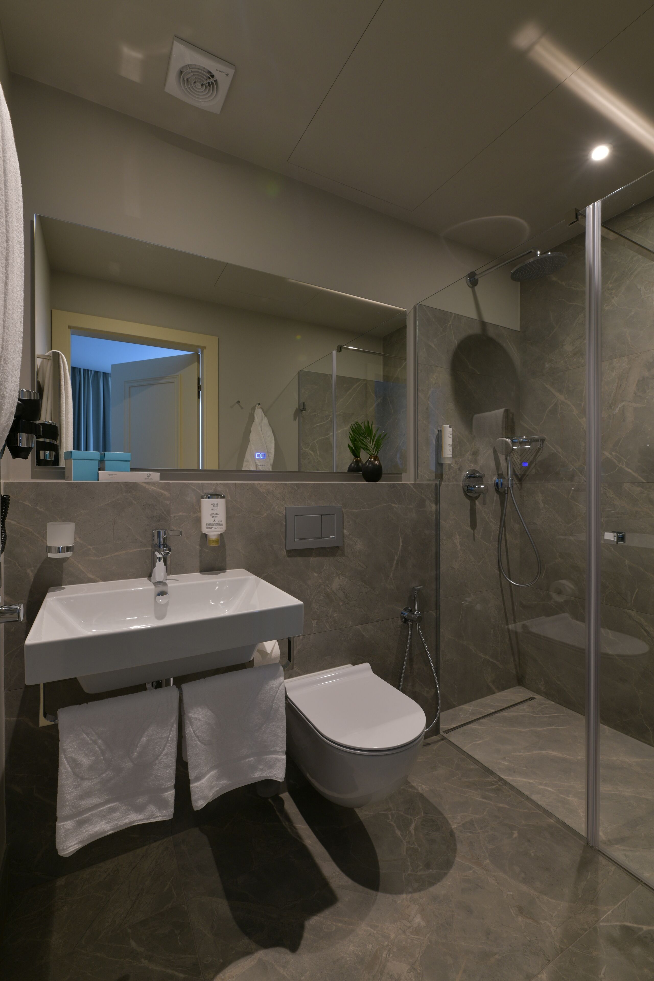 Een moderne badkamer met een wastafel, toilet en een douche met glazen wanden.