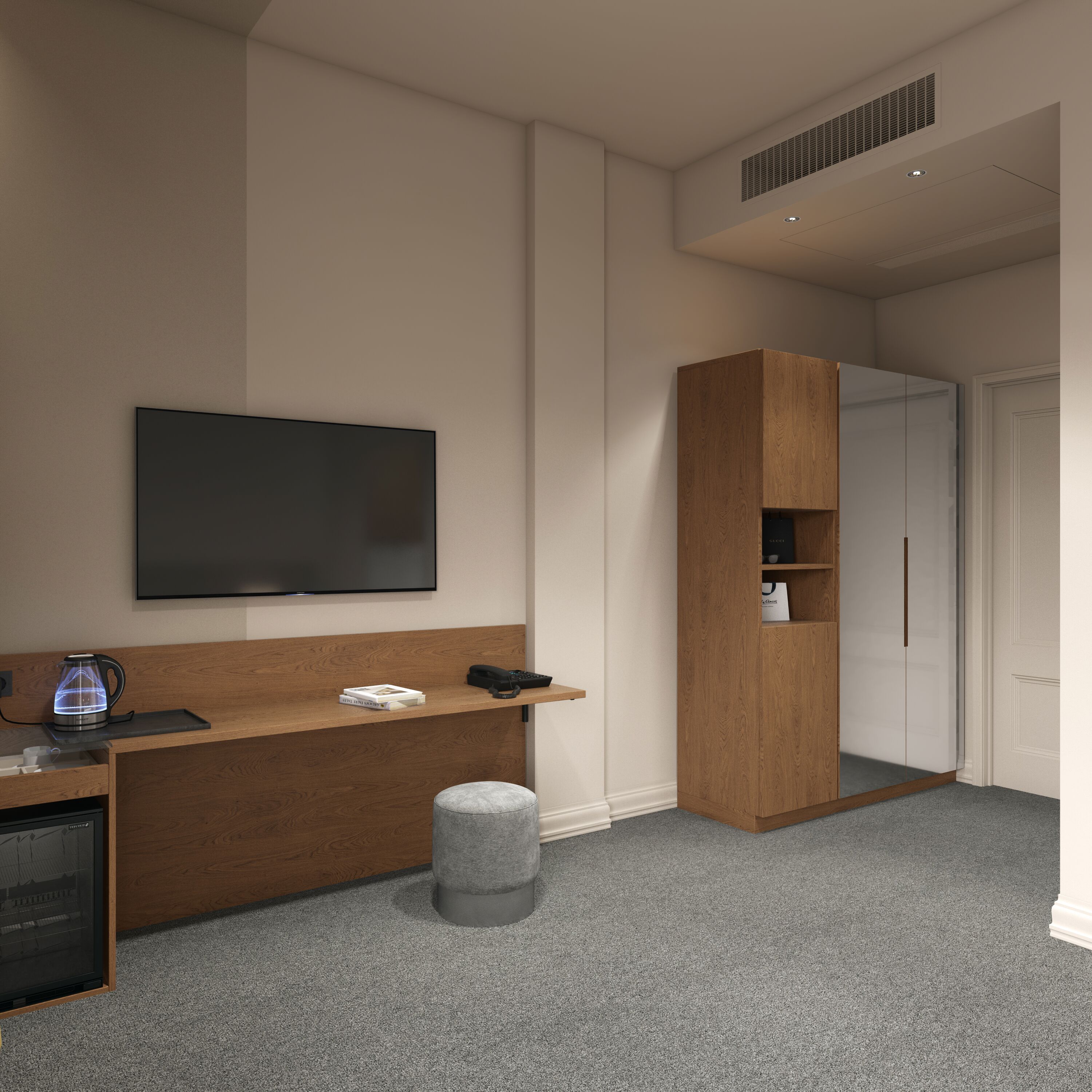 A modern hotel room with a flat-screen TV, a wooden desk, a kettle, a small ottoman, and a wardrobe.
