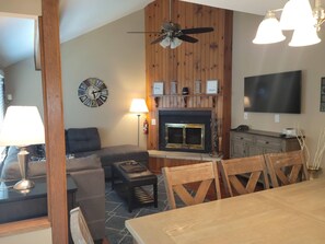 A cozy living room with a fireplace, a sofa, a dining table, and a TV mounted on the wall. - 3 Bedroom, 3 bath townhouse in The Galena Territory (Galena)