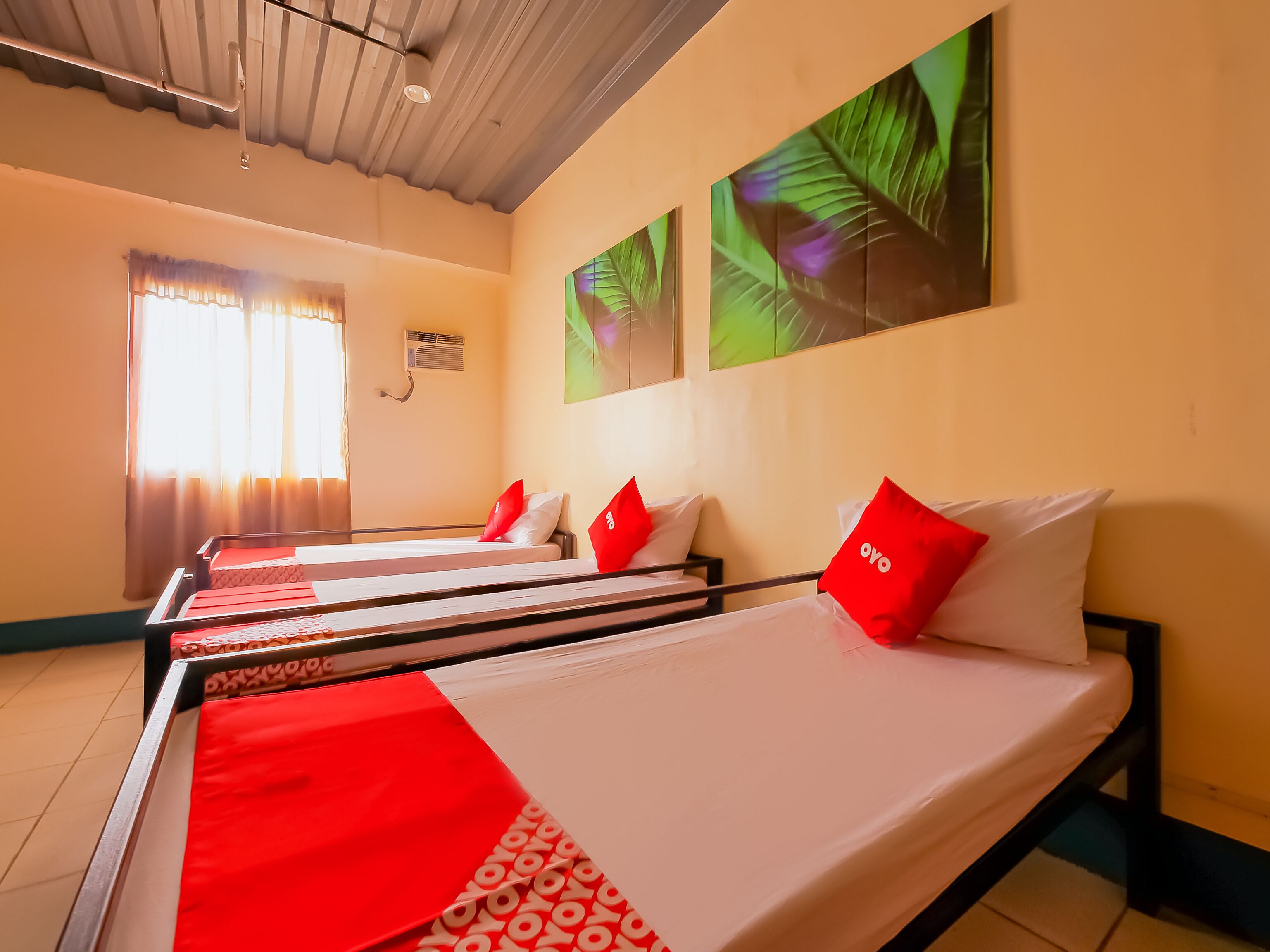 A hotel room with a bed, a window with curtains, and a wall with a leaf pattern.