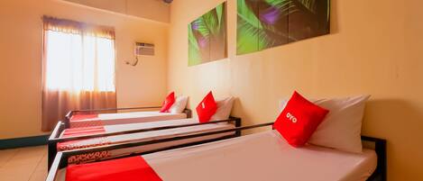 A hotel room with a bed, a window with curtains, and a wall with a leaf pattern.