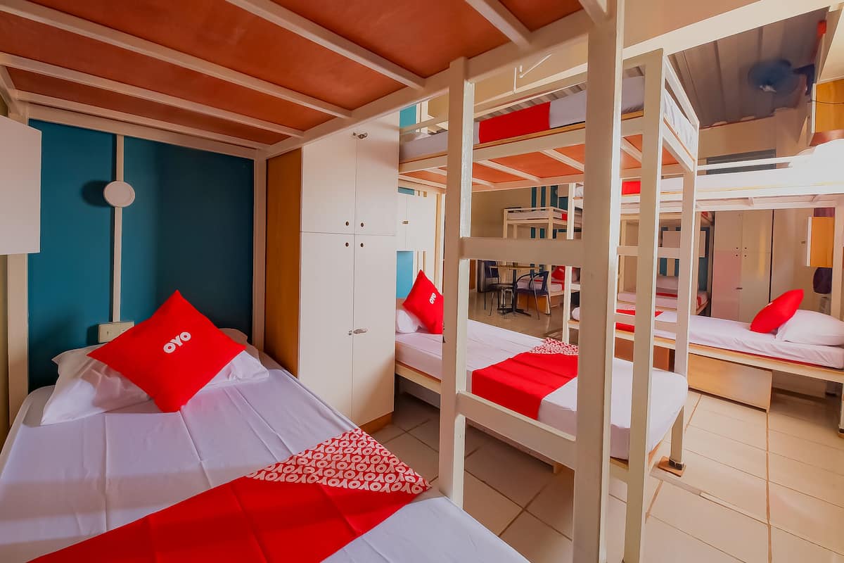 A dormitory room with bunk beds, a desk, and a chair.