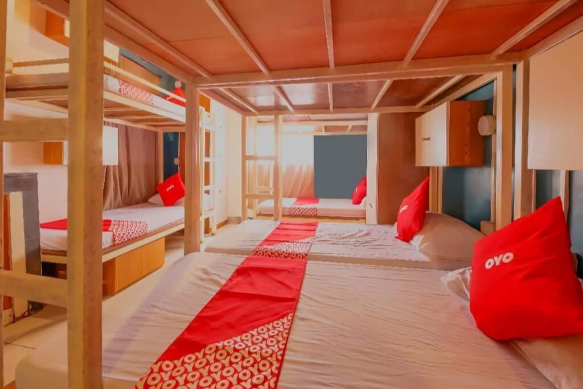 A room with bunk beds, a red patterned bed runner, and a wooden ceiling.