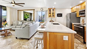 A modern kitchen with a central island, wooden cabinets, and stainless steel appliances.