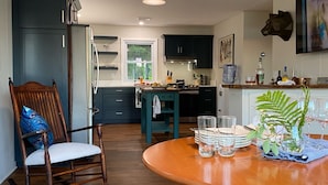 A modern kitchen with dark cabinetry, a wooden dining table, and a rocking chair.
