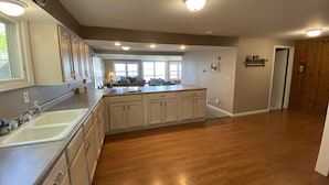 Een ruime keuken met een groot eiland, houten vloeren en uitzicht op de woonkamer.