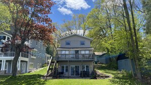 Een tweelaags huis met een balkon, een overdekte patio en een verzorgd gazon.