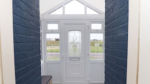 A white door with a glass panel and a decorative design, leading to a tiled entrance area.