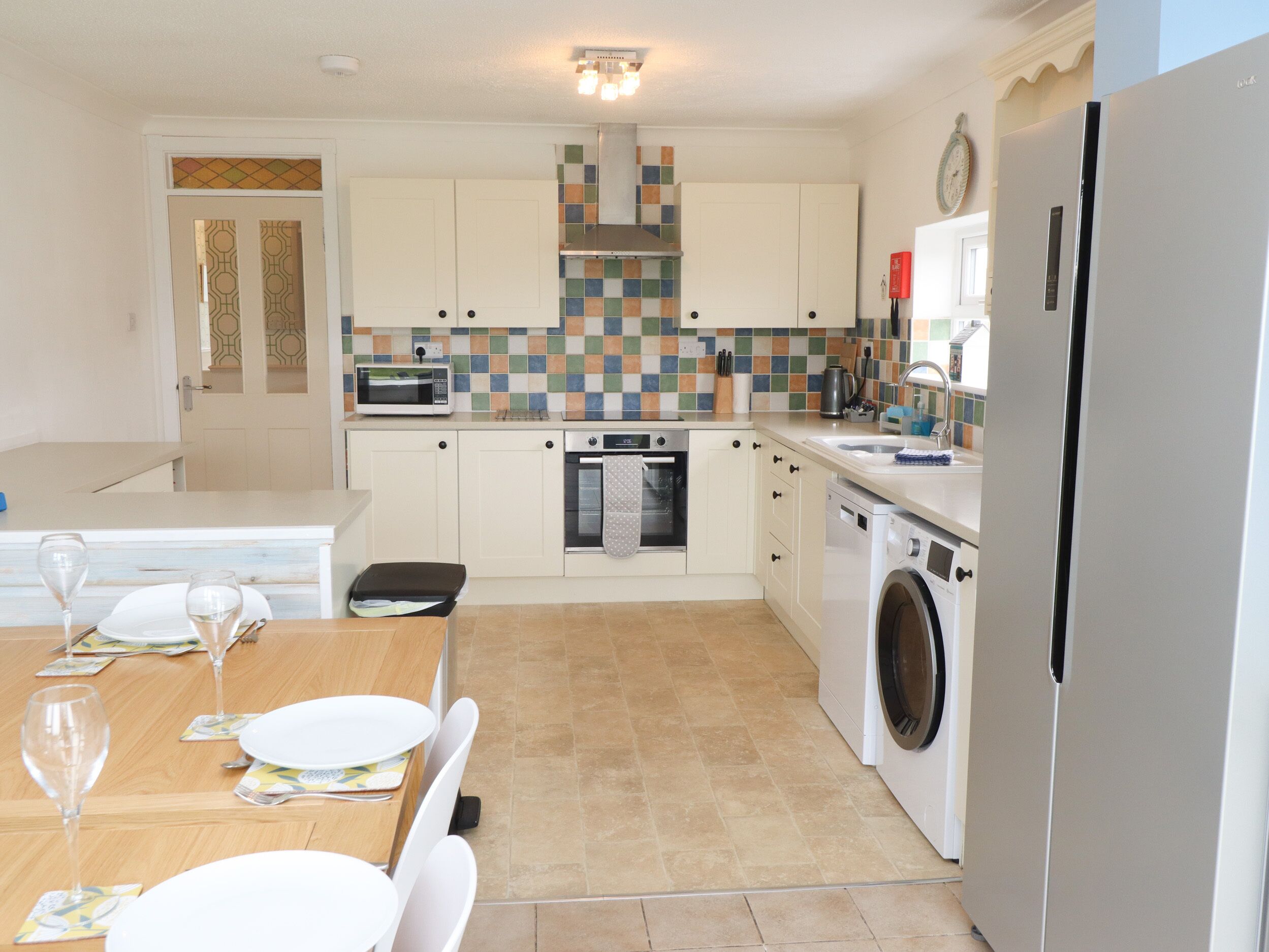A compact kitchen with a microwave, oven, washing machine, and a refrigerator.