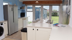 A kitchen with a built-in washing machine, a refrigerator, a sink, and a dining area with a table set for four.