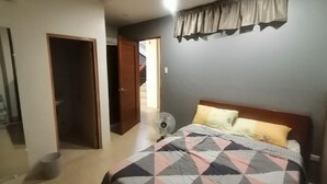 A bedroom with a bed, a fan, and a door leading to another room. - Capital O 811 Tri A's Building (Olongapo)