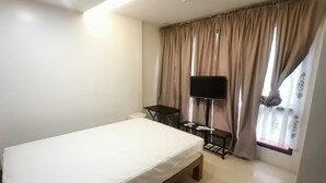 A hotel room with a single bed, a small table, a TV, and a window with curtains. - Capital O 811 Tri A's Building (Olongapo)