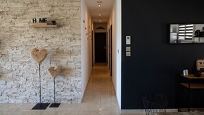 A modern interior with a stone wall, a hallway leading to a dark room, and a black wall with a mirror and a sign. - Villa "La Romarine" for 6 people in a quiet location with magnificent views  (Salernes)