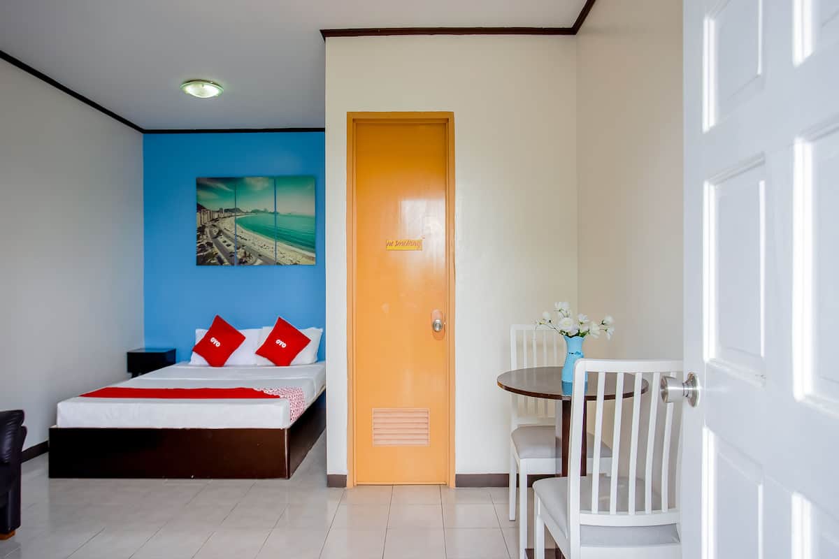 Een hotelkamer met een bed, een bureau, een stoel en een deur.