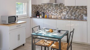 Une cuisine moderne avec une table à manger en verre, des meubles blancs et un plafond en bois.