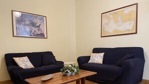Una sala de estar con dos sofás azul oscuro, una mesa de centro de madera con un centro de mesa floral y un mapa en la pared.