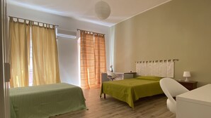 Una habitación con dos camas, un escritorio, una silla y una lámpara.