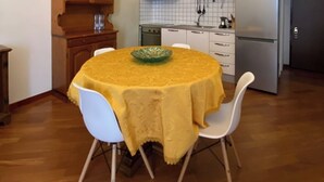 Un comedor con una mesa redonda cubierta con mantel amarillo, rodeado de sillas blancas.