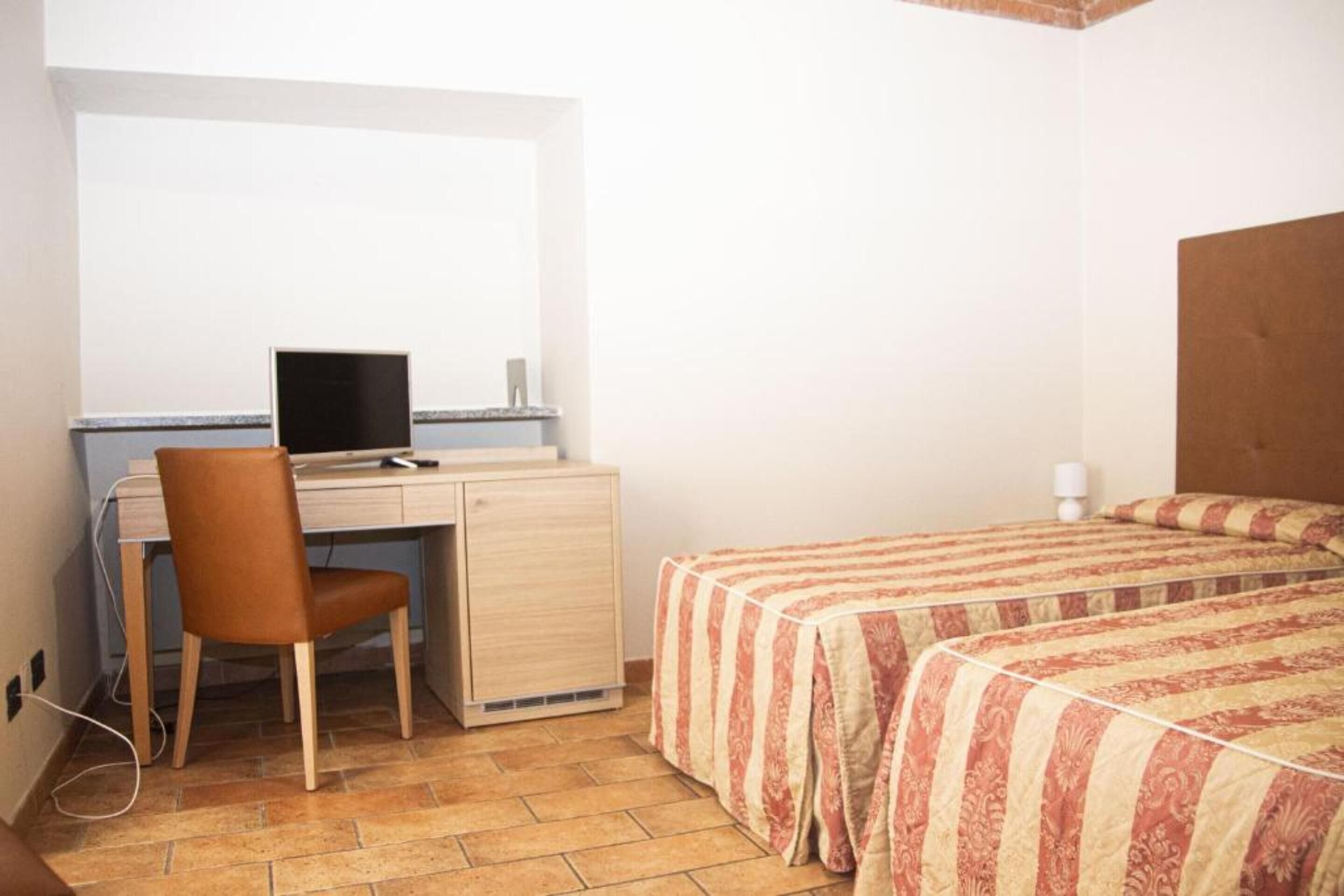 Een slaapkamer met een bureau, stoel en twee bedden.