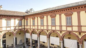 Un patio con mobiliario exterior, columnas y techo de tejas.