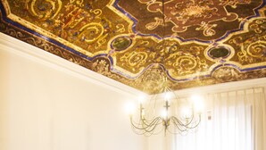 Una habitación de hotel con una cama grande, una mesita de noche, una araña y un techo decorativo.