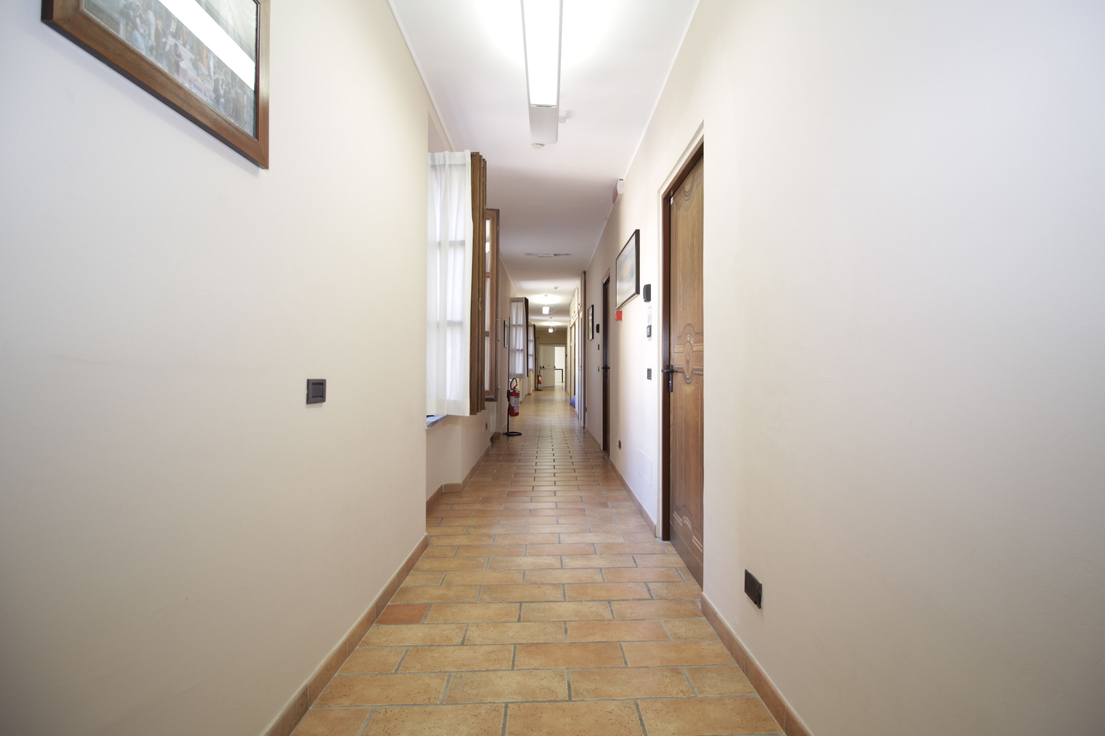 A hallway with tiled flooring, white walls, and wooden doors.