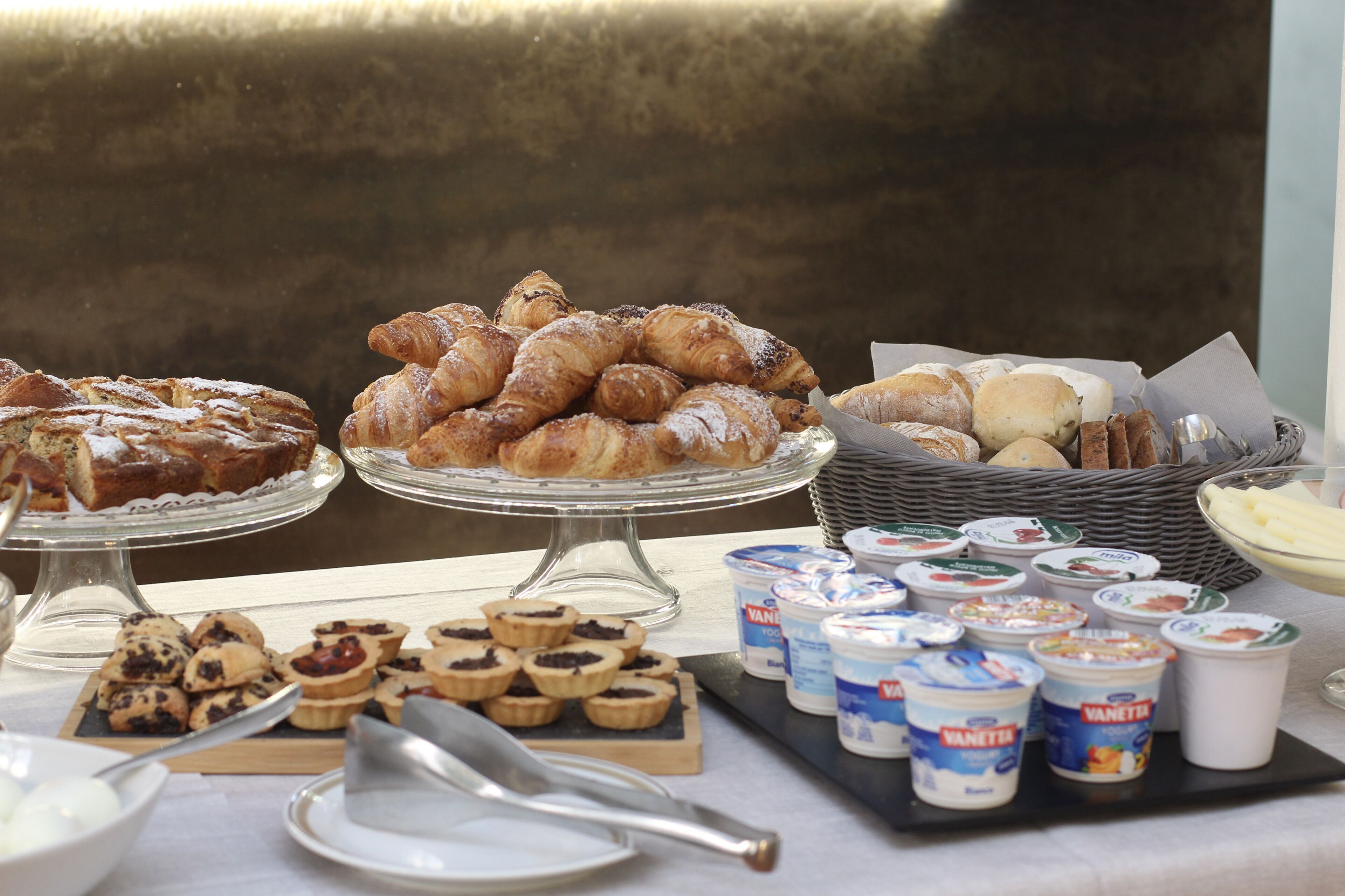 A buffet table with various pastries, tarts, and yogurt cups.