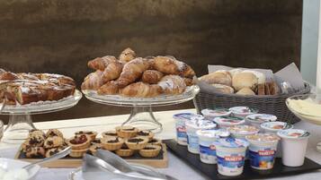 A buffet table with various pastries, tarts, and yogurt cups.
