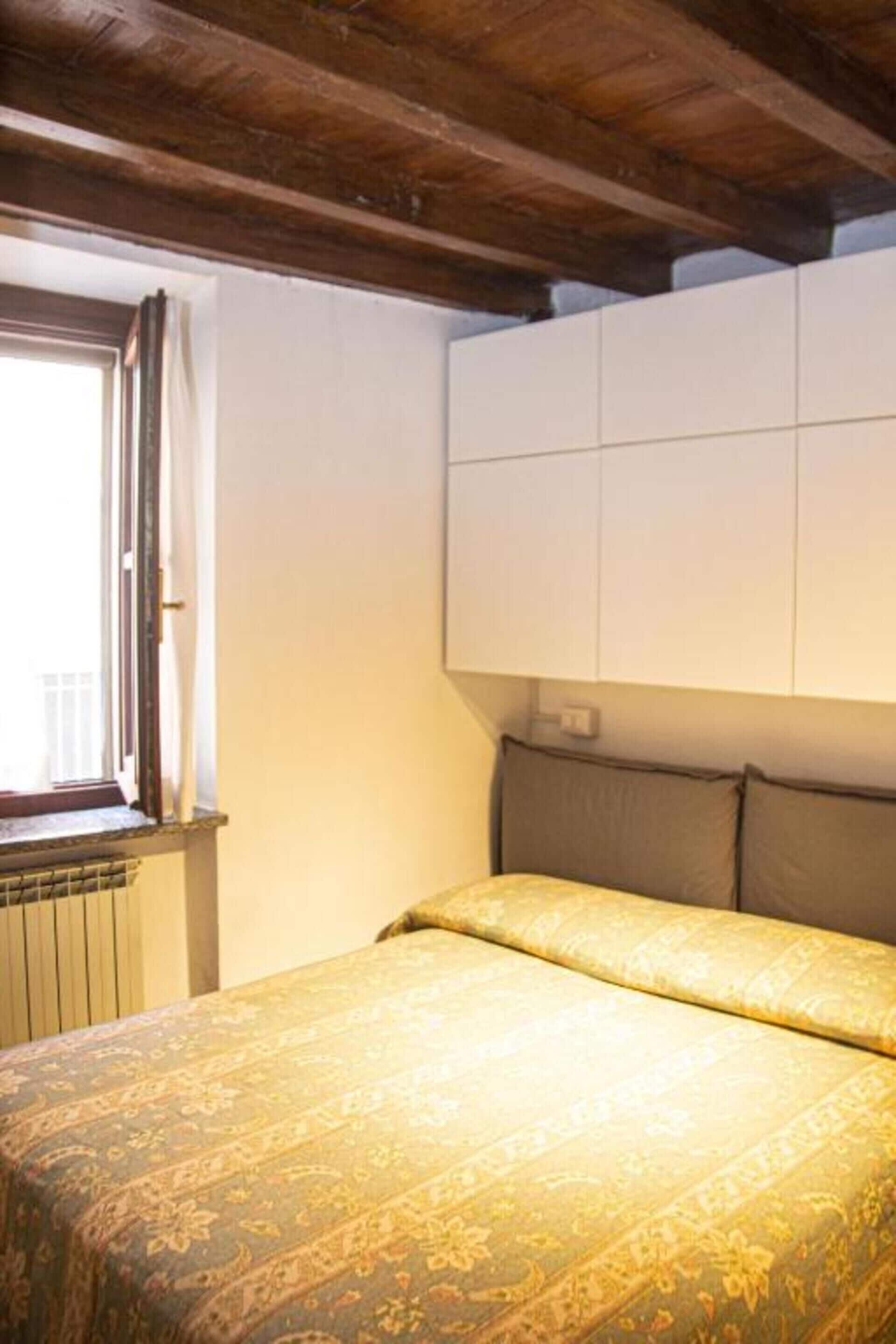 Ein Schlafzimmer mit einem Bett, einem Fenster und einem weißen Kleiderschrank.