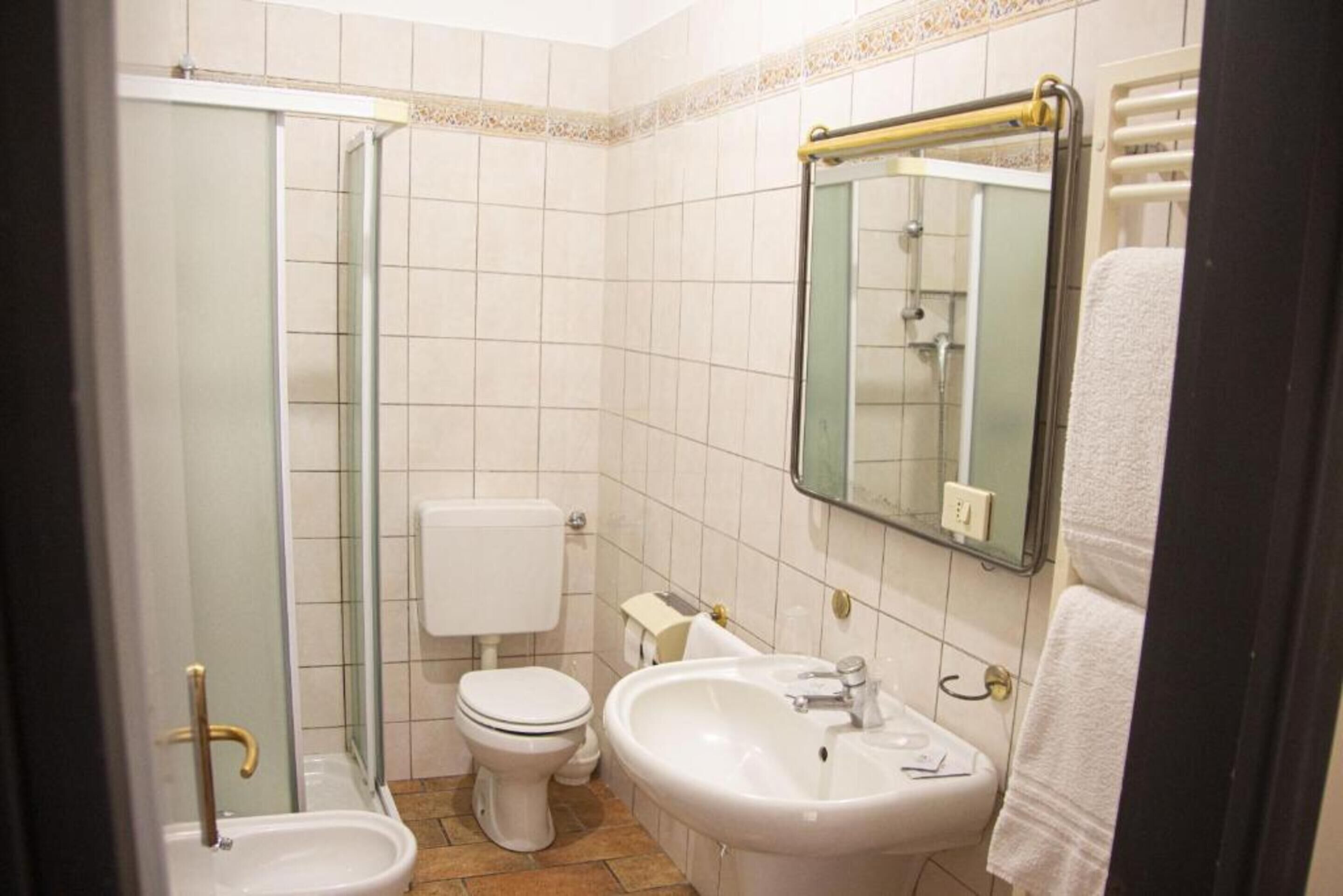 A bathroom with a glass shower enclosure, a toilet, a sink, and a mirror.
