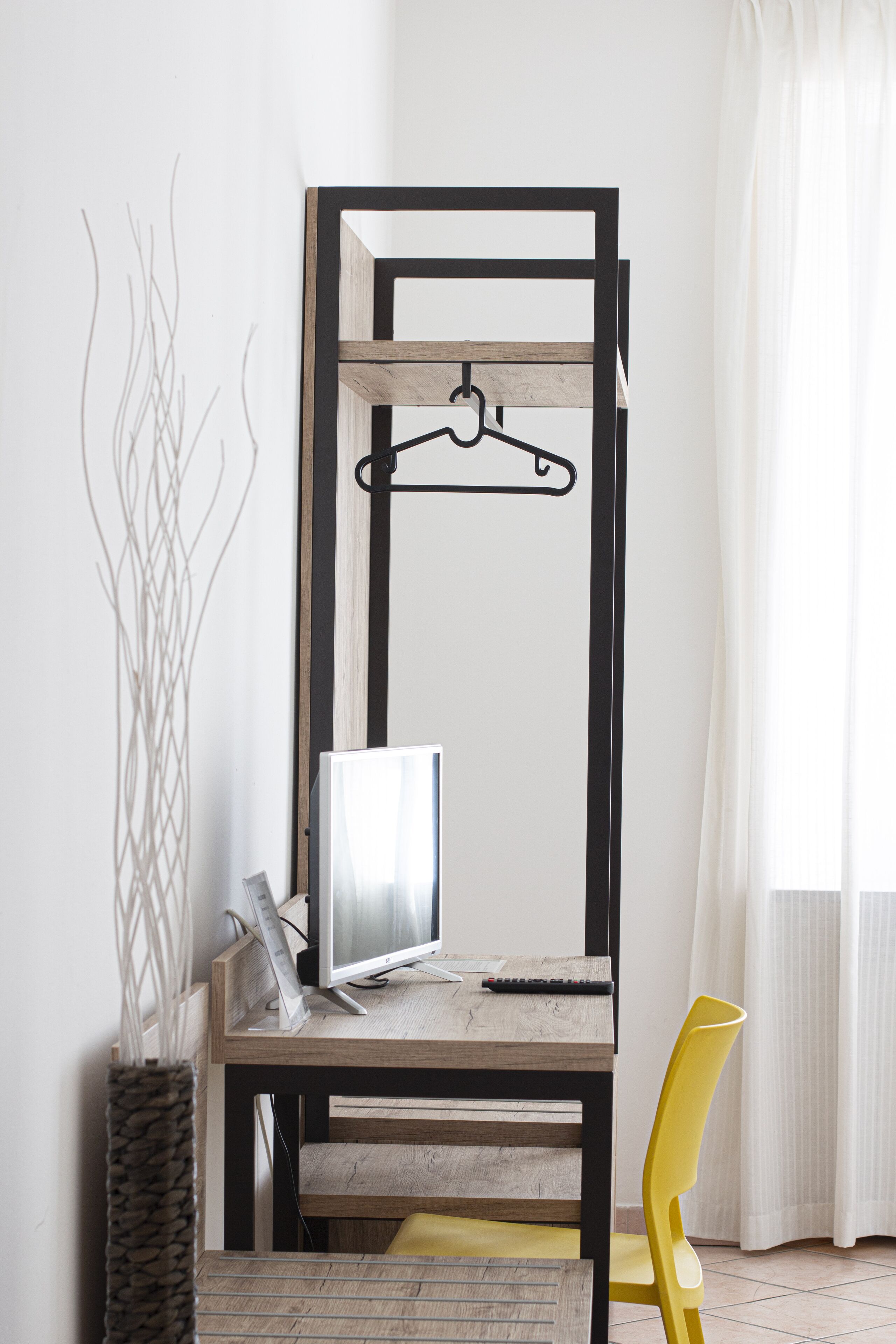 A workspace with a wooden desk, a computer, a yellow chair, and a hanging organizer.